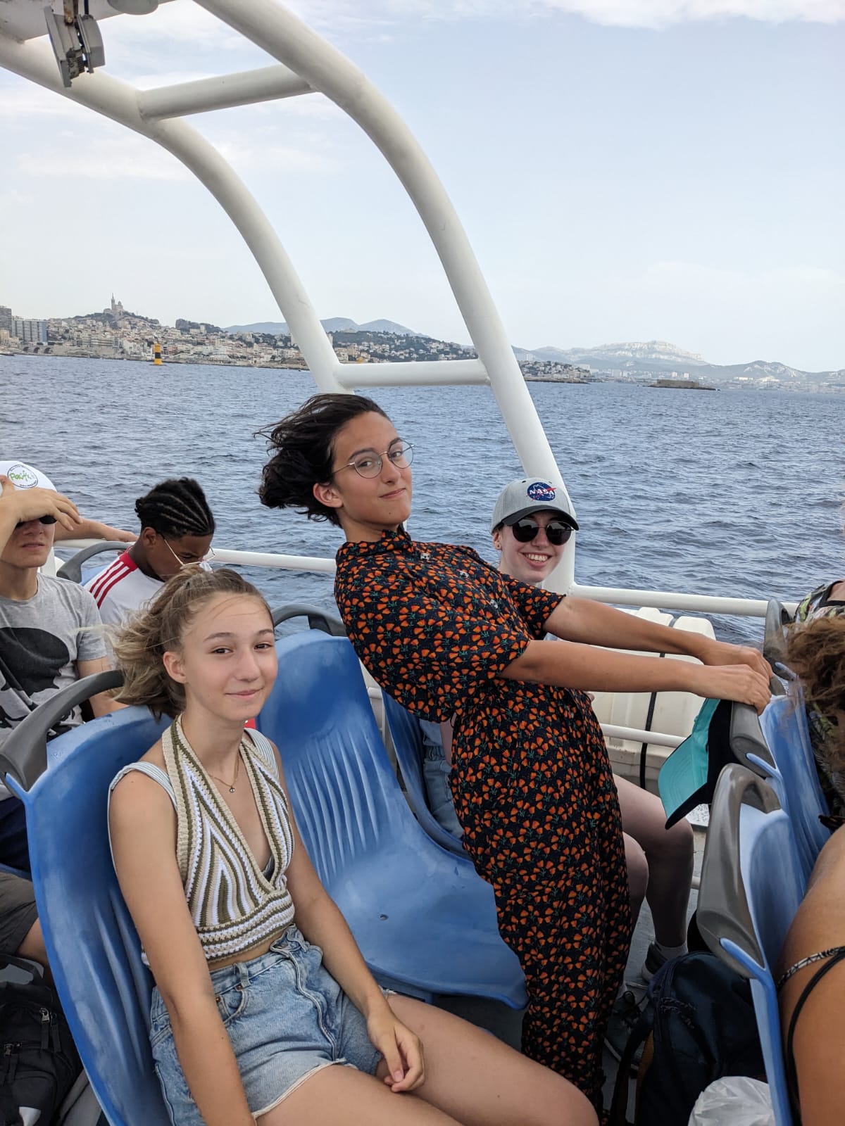 Trois participant et participantes Tandem sur la navette vers les îles du Frioul avec la bonne mère en arrière plan