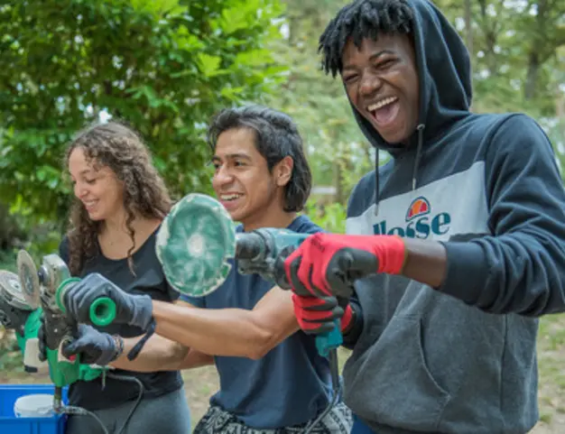 Trois jeunes utilisent des outils sur un chantier